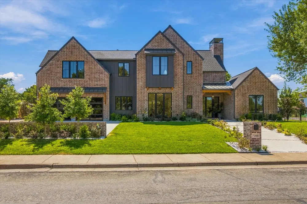 Brick and board-and-batten new build behind a manicured front lawn