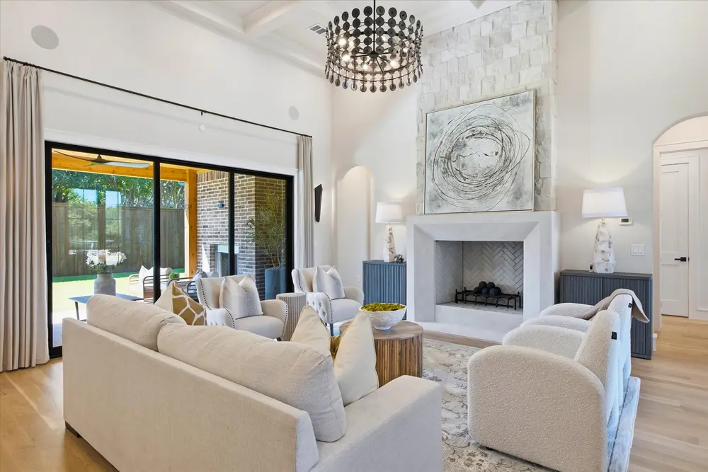 Living room with a stone fireplace, iron chandelier and sliding doors to the patio