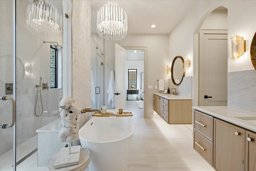 Primary bath with a freestanding tub, glass shower and crystal chandeliers