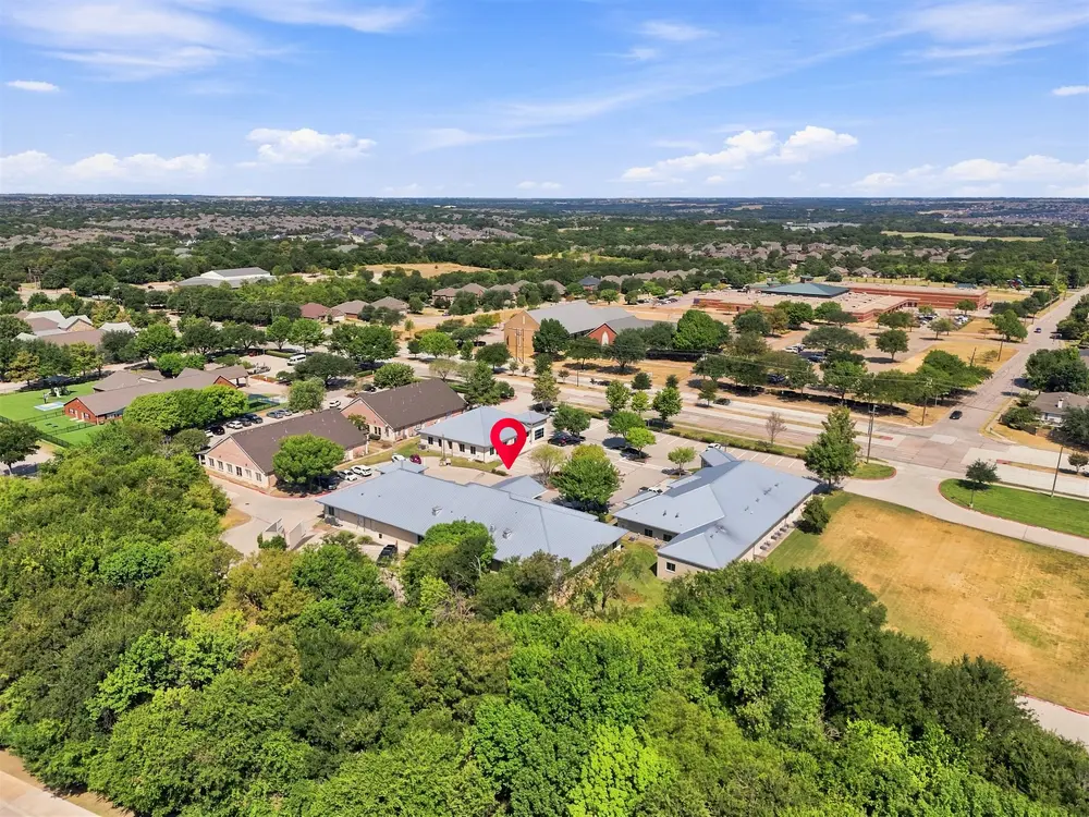 High aerial of an office park and the surrounding neighborhoods, with a pin marking the subject building