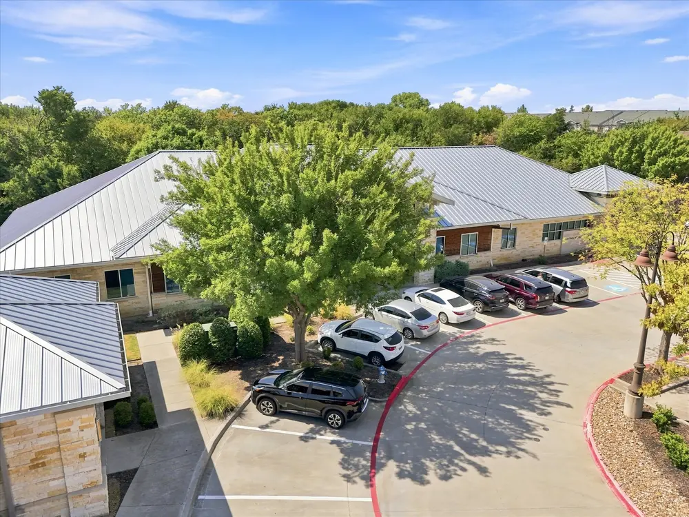 Low aerial over an office building entry drive and curved parking lot