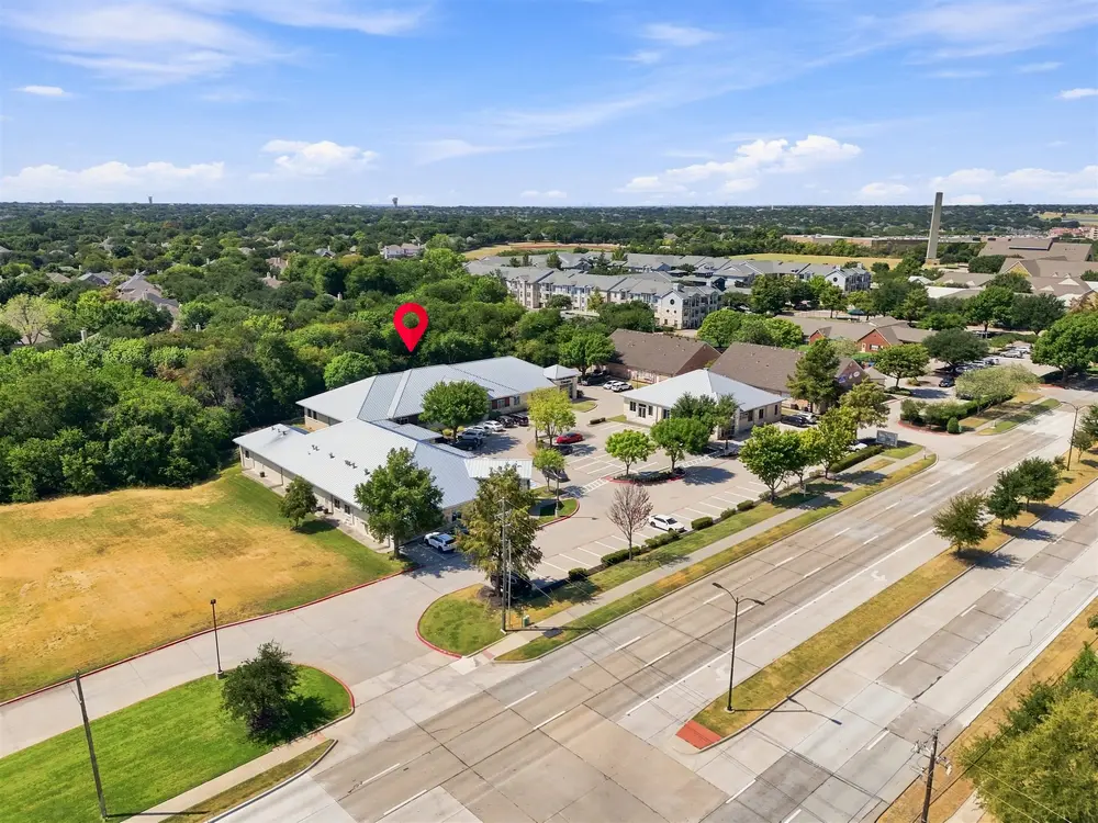 Aerial of an office park beside a divided parkway, with a pin marking the subject building