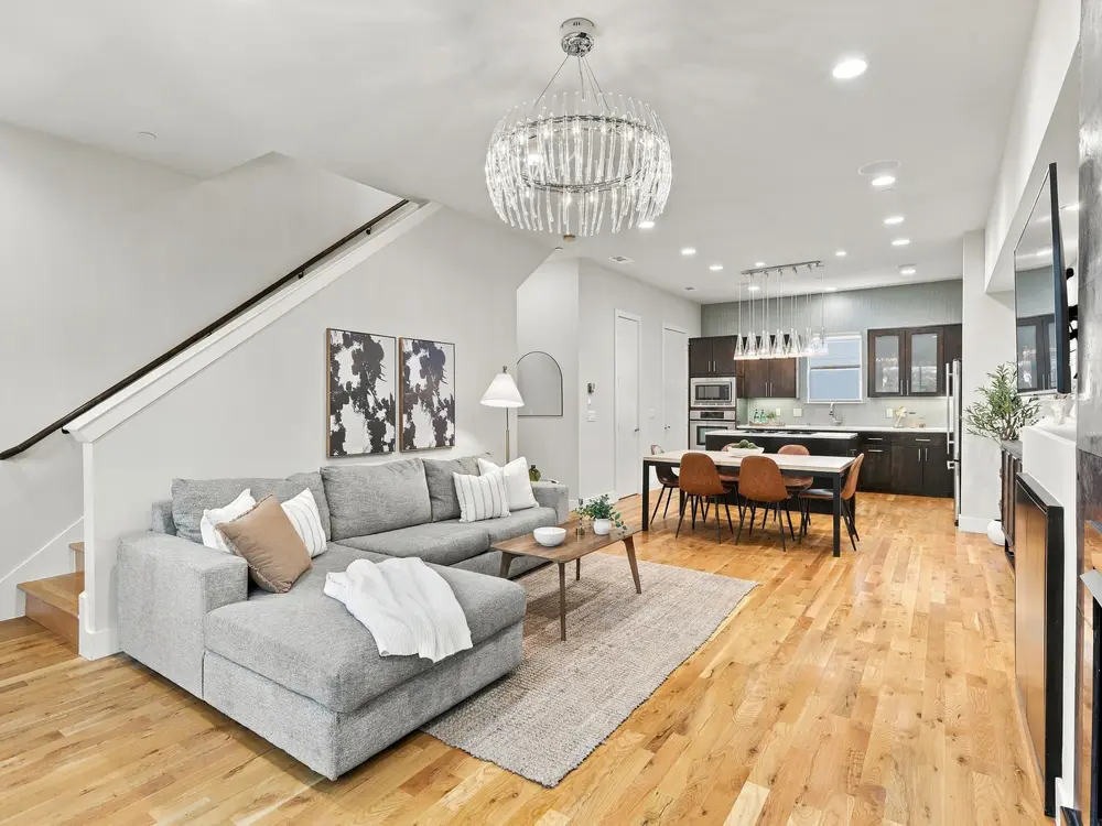 Open living room with a gray sectional, chandelier and kitchen beyond