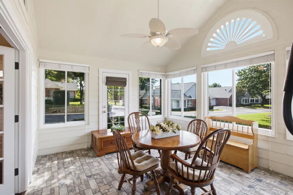 Sunroom with brick floors, an arched window and a round dining table